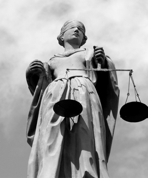 A black and white image of the statue of Lady Justice, blindfolded and holding balanced scales.